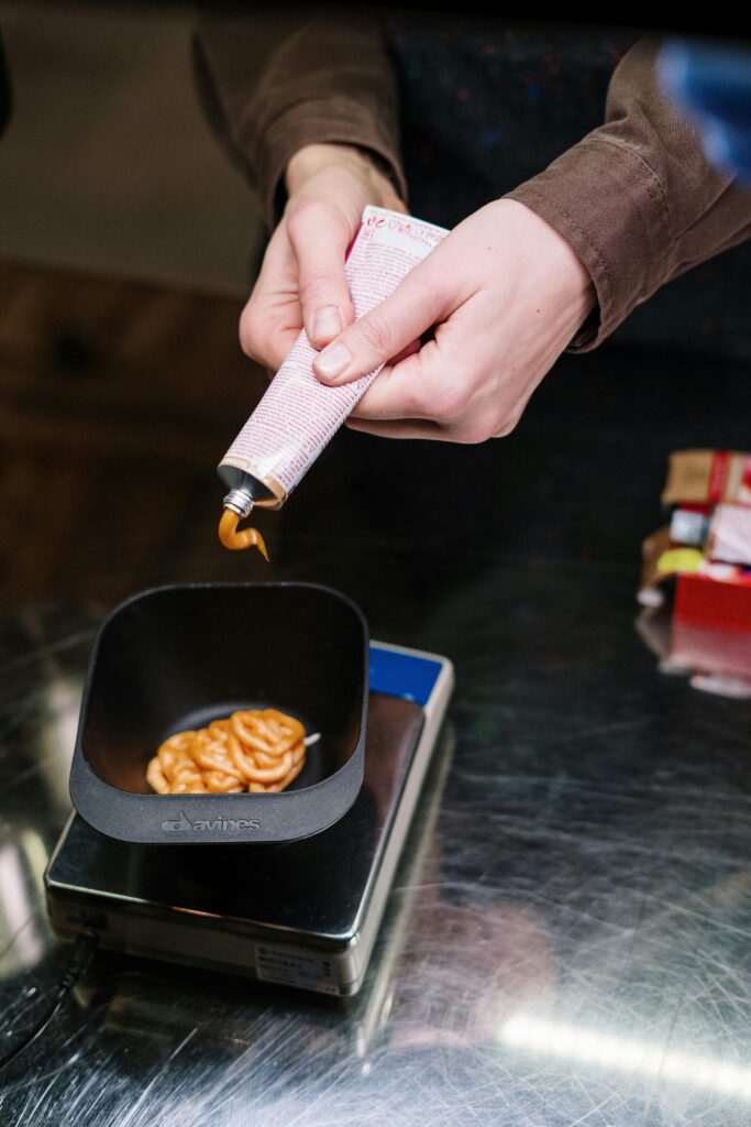 Person Holding White Paper Near Black Ceramic Bowl With Brown Food